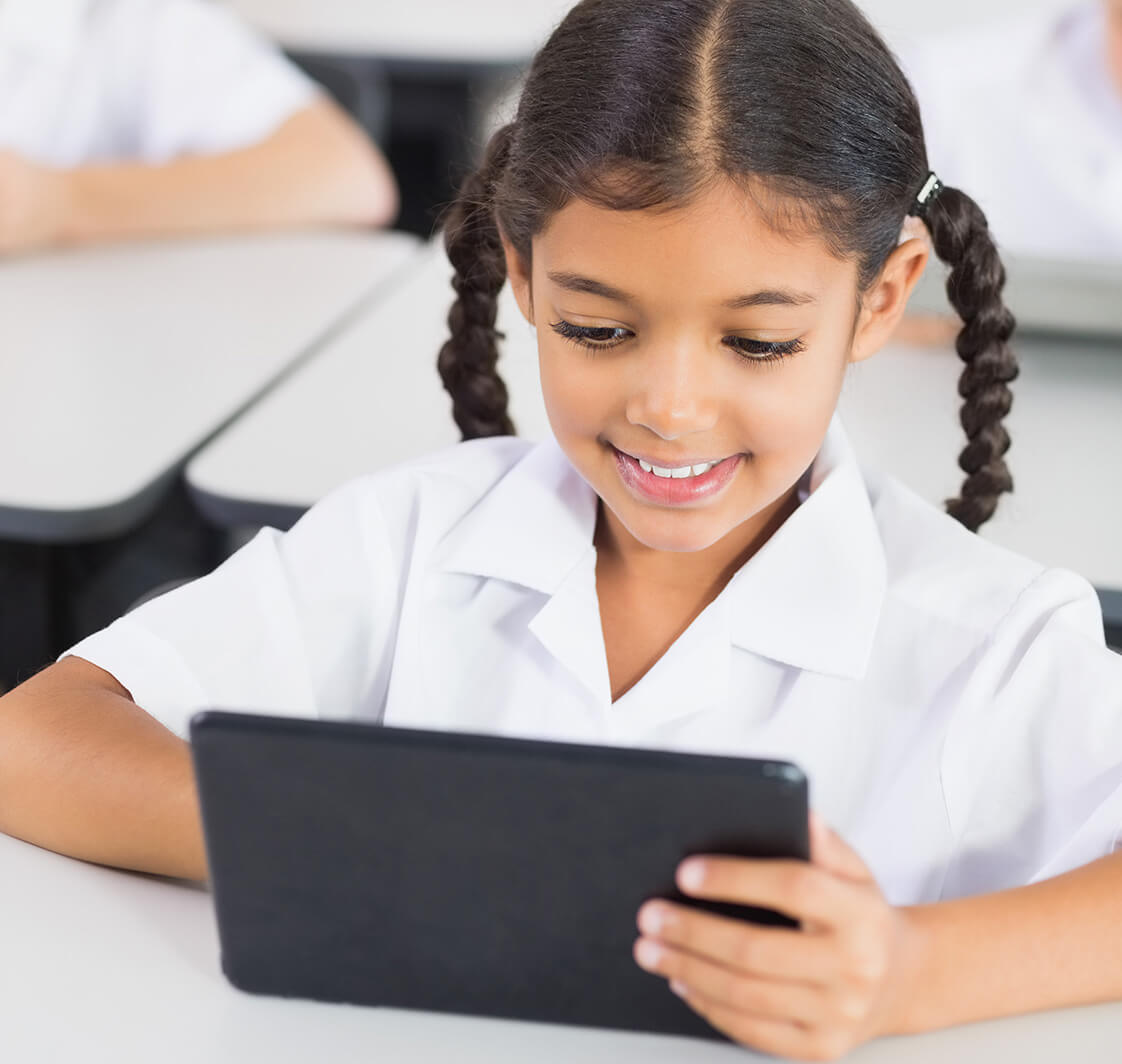 Schoolgirl using digital tablet in classroom.