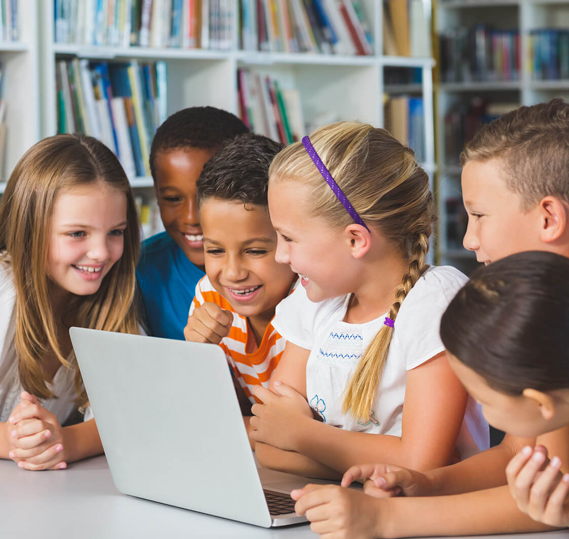 Children using a laptop in a classroom.