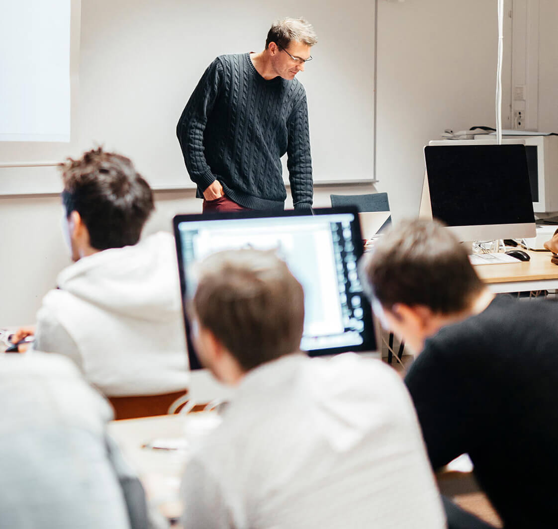 Teacher overseeing students using computers.