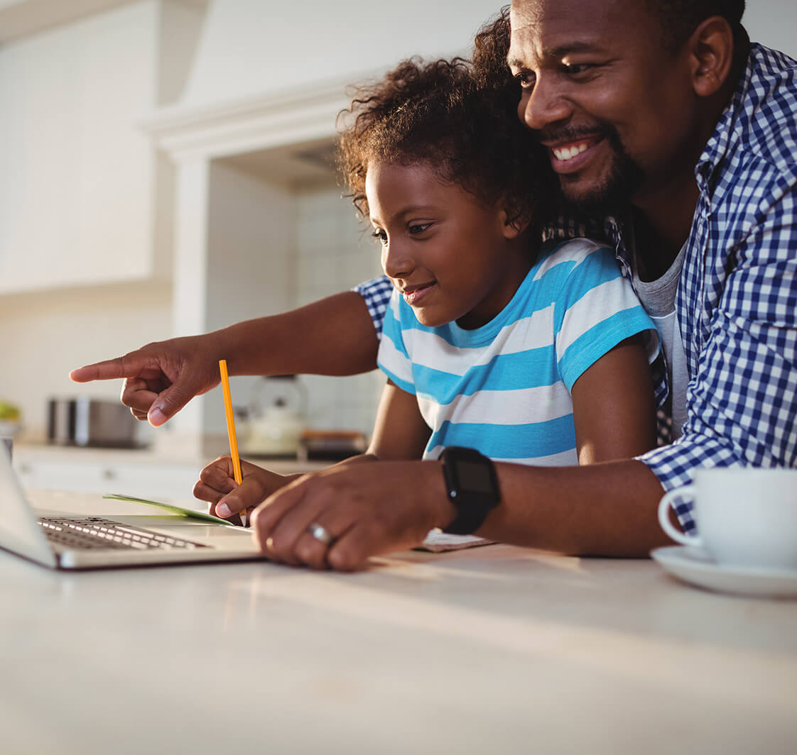 Father and daughter at home using a laptop.