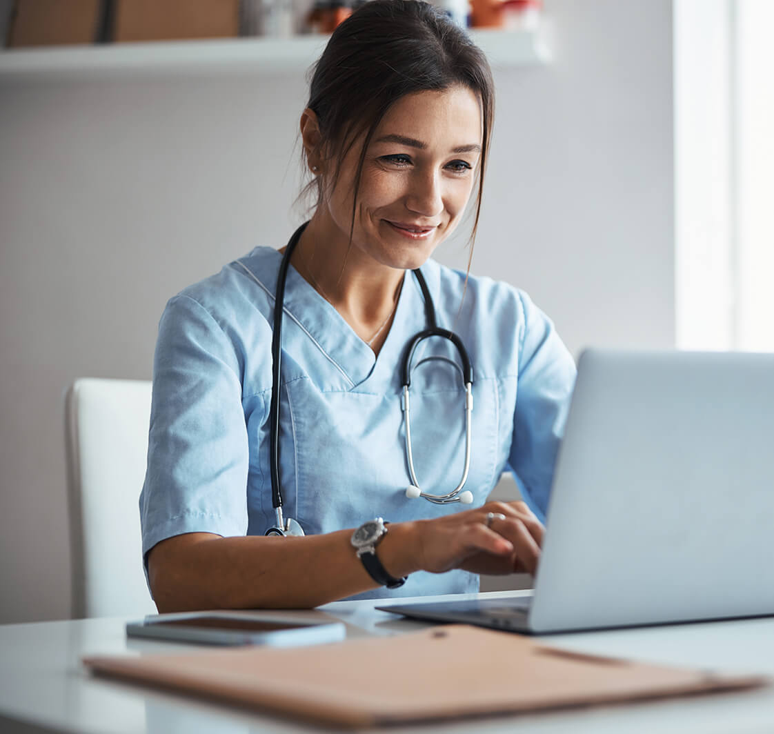 Joyful female doctor using notebook in clinic