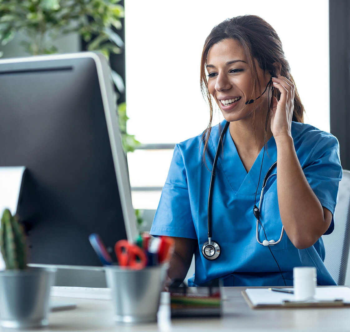 Female doctor talking with earphone while explaining medical treatment to patient through a video call with computer in the consultation.