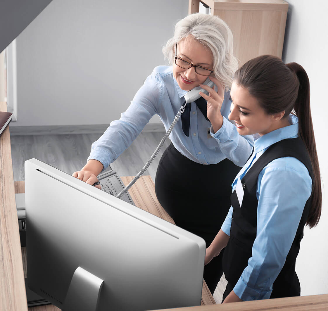 Female receptionist with trainee in hotel.