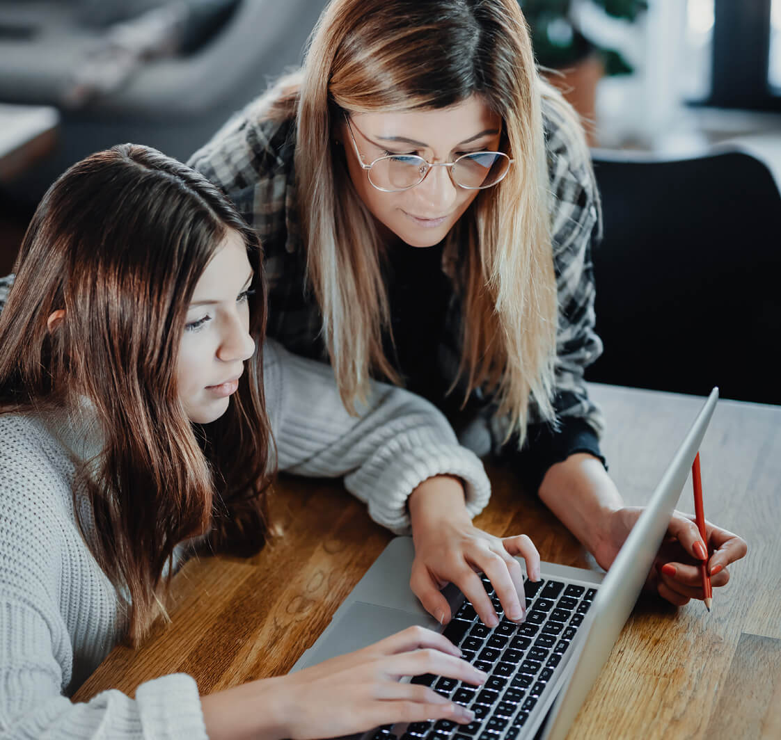 Mother and daughter working on a laptop at home.