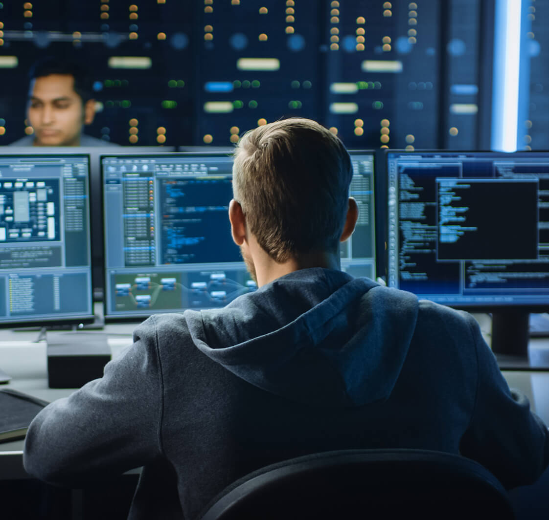 IT Specialist Works on Personal Computer with Screens Showing Software Program with Coding Language Interface. In the Background Technical Room of Data Center with Professional Working.