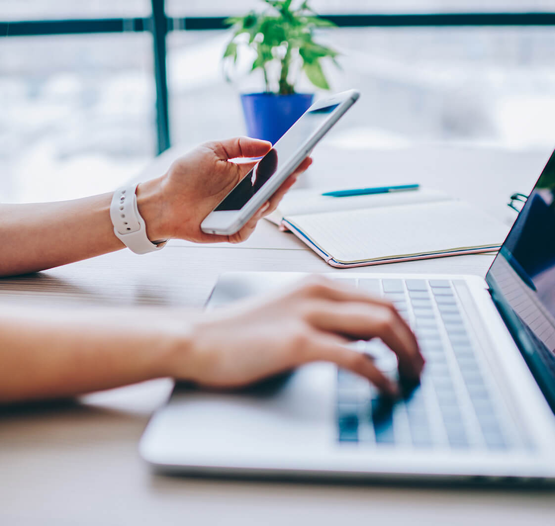 Cropped image of female holding smartphone getting message with confirmation making transaction on laptop computer,woman using mobile phone app for synchronizing data with netbook via bluetooth
