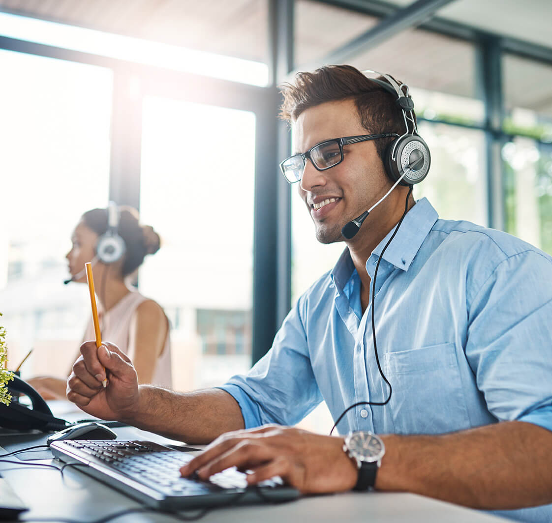 Theyve got the answers youre looking for. Cropped shot of a handsome young man working in a call center with a female colleague in the background.