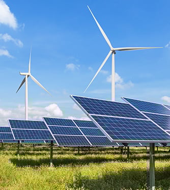 Solar panels and wind turbines generating electricity in power station green energy renewable with blue sky background.