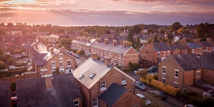 Sun setting with atmospheric effect over traditional British houses and tree lined streets. Dramatic, warm lighting creates a homely mood.