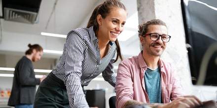 two people in an office looking at a laptop