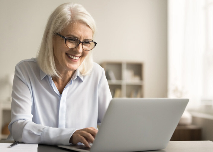 Woman working for Brainkind smiling at someone online on her laptop