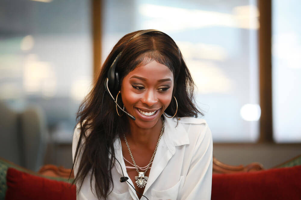 Smiling woman wearing a headset in a university office, utilising cloud technology to streamline call processing and eliminate equipment bottlenecks.