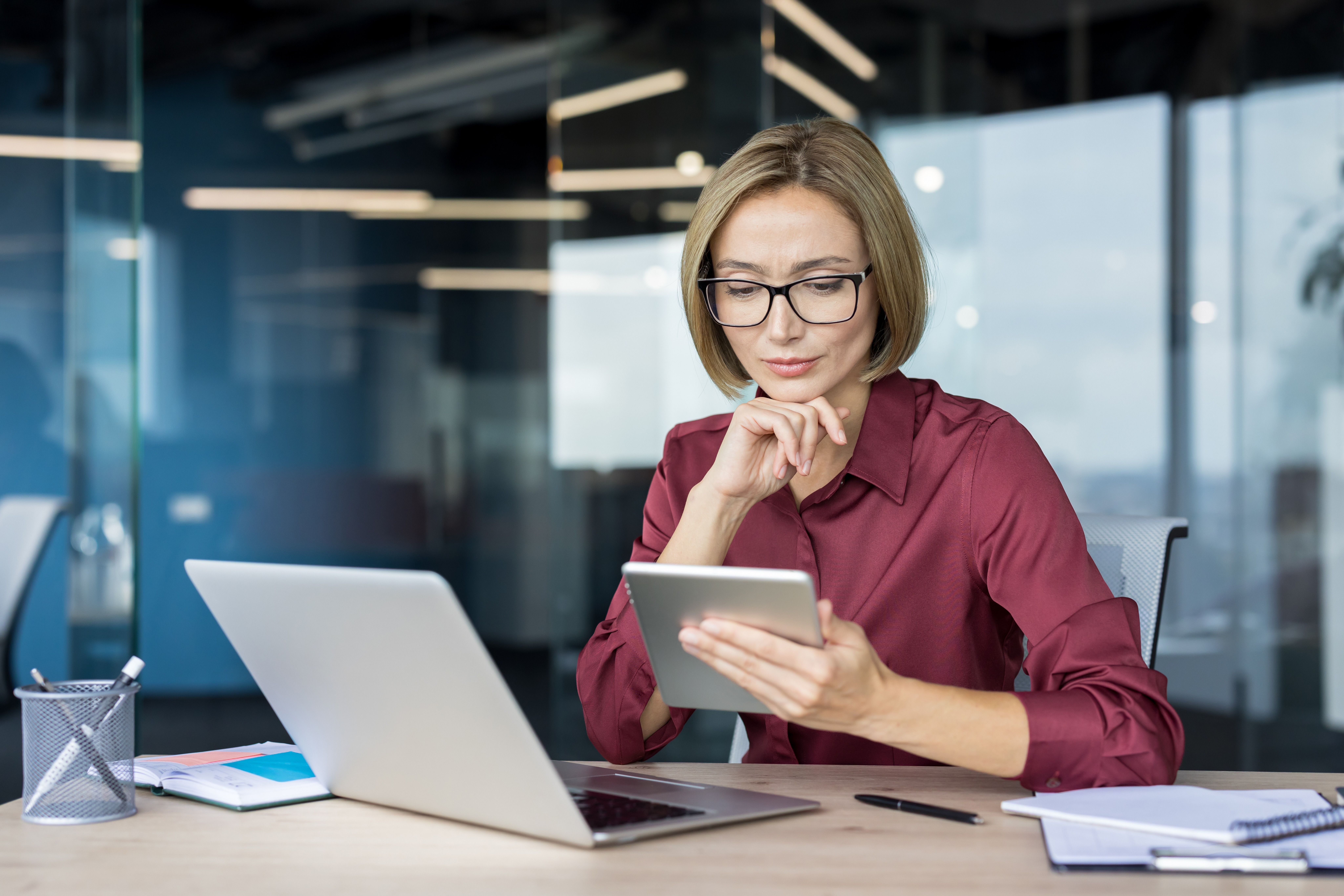 Female office working checking information on a digital tablet against information on a laptop