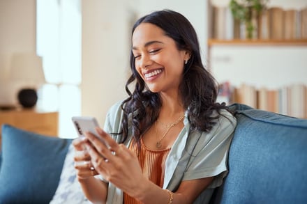 A happy house tenant is using an app on her phone to report a home issue to her housing provider