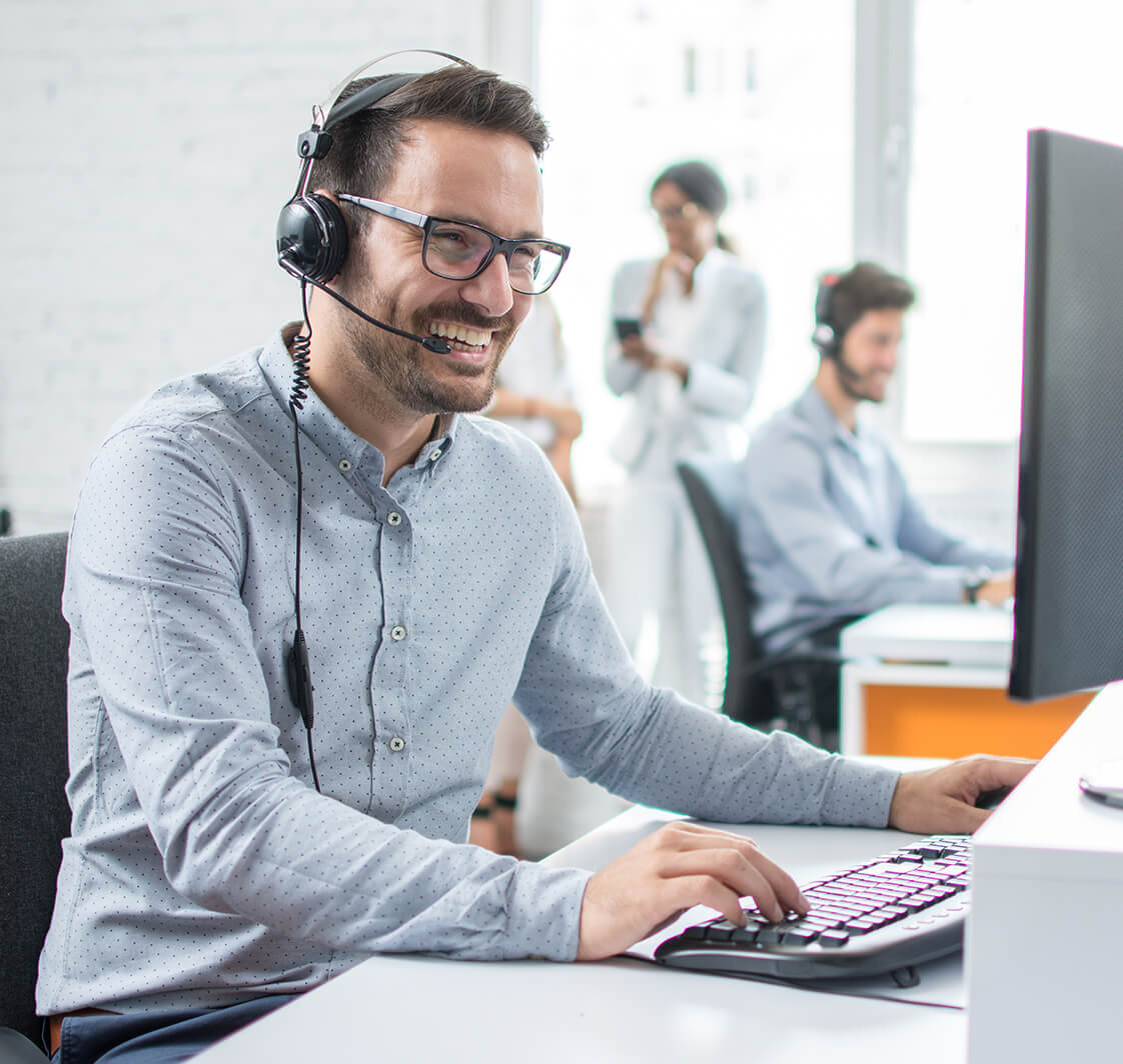 Smiling customer support operator with hands-free headset working in the office.