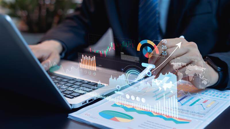 Hands above a laptop keyboard pointing to a rising digital-growth icon emerging from a strategic growth plan page beside the laptop.